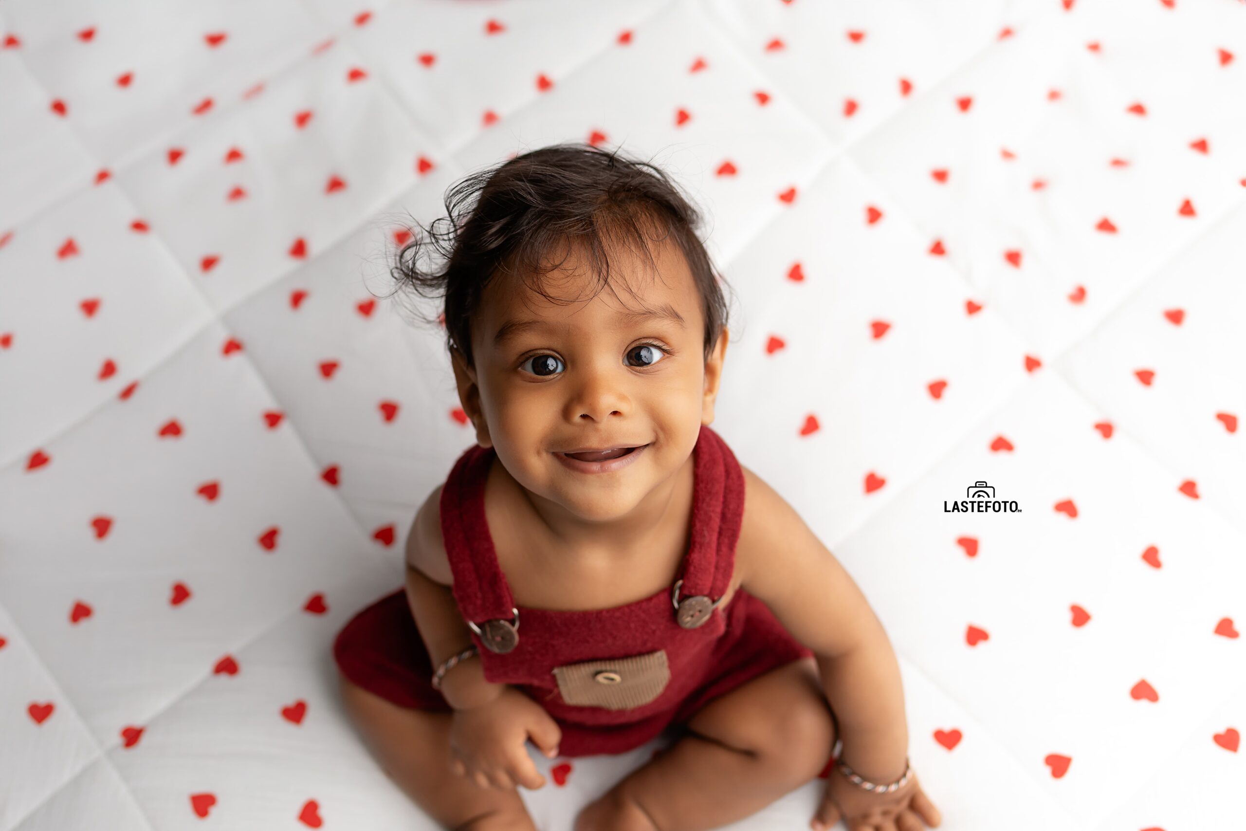 Early Childhood Development: Essential for the Child or Peace of Mind for the Mother? 1 Smiling baby sitting on a heart-patterned blanket – early childhood development in Tallinn