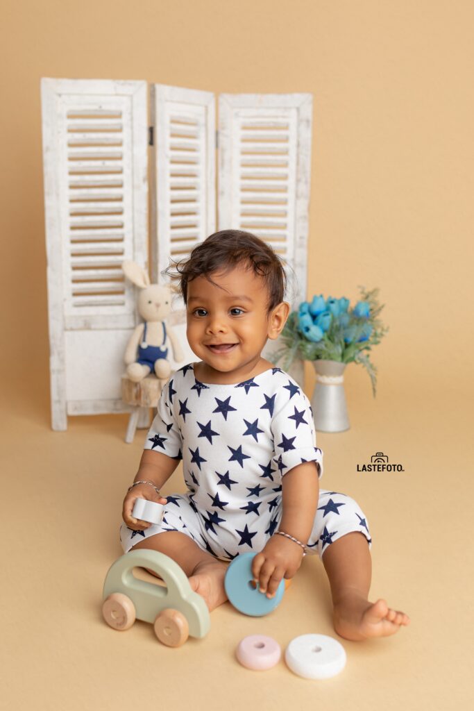 Early Childhood Development: Essential for the Child or Peace of Mind for the Mother? 5 Smiling baby in star-patterned outfit sitting on the floor with colorful toy pieces and a wooden car – early childhood development in Tallinn