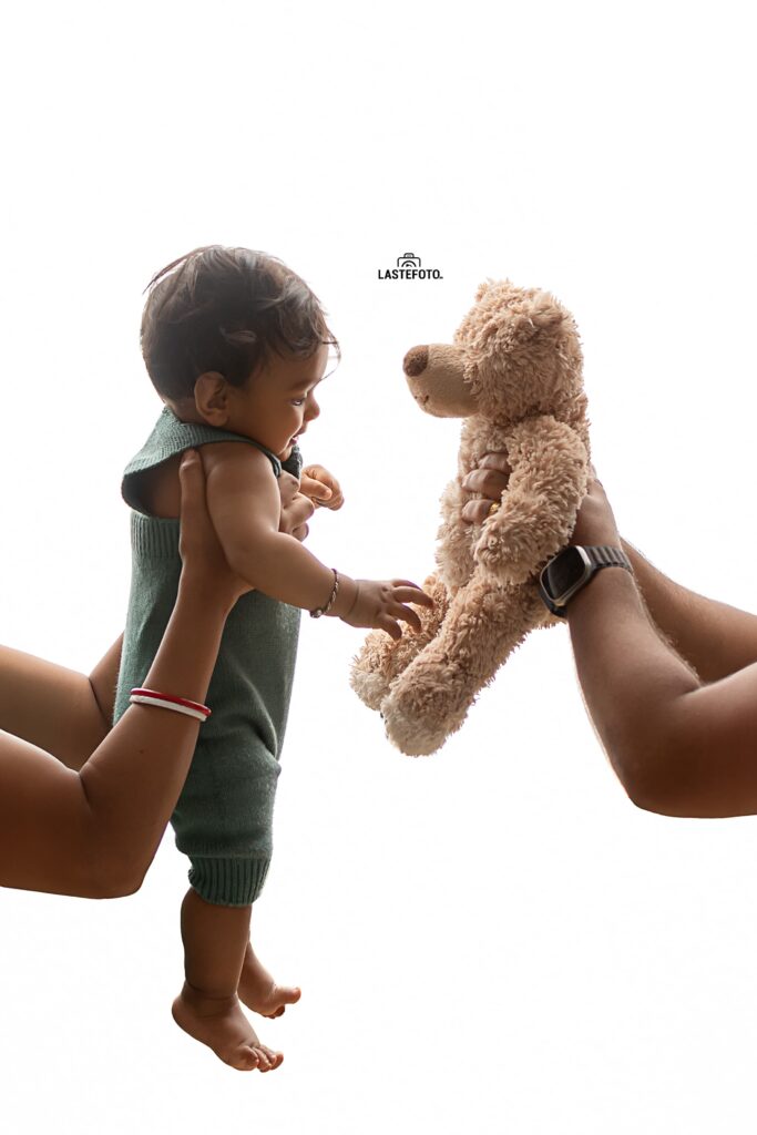 Early Childhood Development: Essential for the Child or Peace of Mind for the Mother? 6 Baby in green romper reaching towards a teddy bear held by an adult – early child development in Tallinn