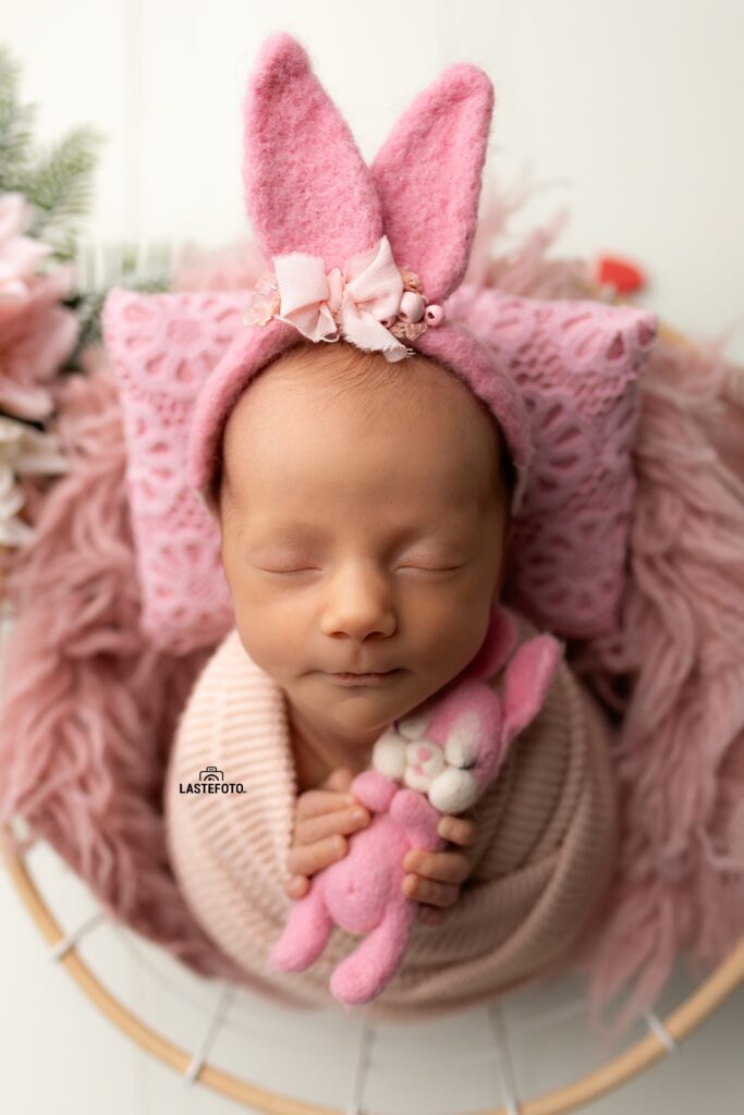 Newborn Twins Photoshoot: 6 Practical Tips for Calm, Confident Planning and Preparation 4 Newborn Twins Photoshoot: sleeping baby girl in a pink bunny-ears headband, swaddled in light knit, holding a felt bunny, close-up in a round basket