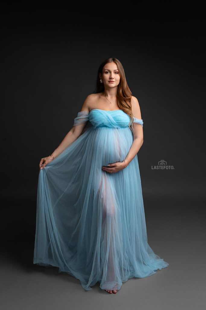 When to Do a Maternity Photoshoot: The Best Timing and 7 Things Most People Don’t Talk About 5 When to do a maternity photoshoot — studio portrait of a pregnant woman in a light blue flowing dress on a dark background